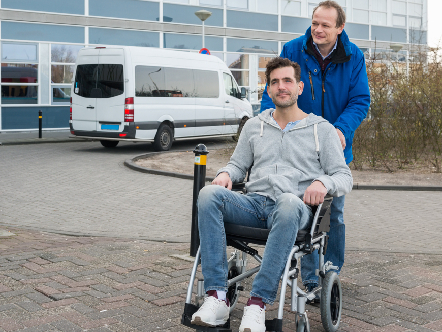 Middle age male pushing a man in a wheelchair outside